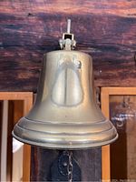 Front view of large brass bell mounted on wood