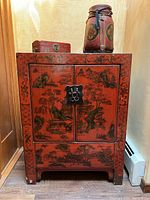 Front view of red lacquer cabinet with boxes on top