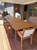 Full-length view of teak table with chairs and bench under covered porch