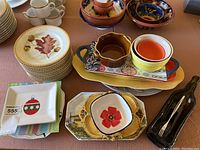 Overview of assorted serving plates, bowls, and platters showing different sizes, colors, and designs including holiday-themed plates and ceramic bowls.