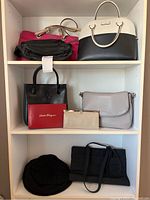 Multiple handbags, clutch, box and hat arranged on shelving