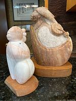 Front view of two Native American stone sculptures on wooden bases, showing detail and scale.