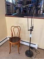 Full view of the bent wood chair and Restoration Hardware floor lamp together, showing the height and style of the lamp and the chair's shape and finish.