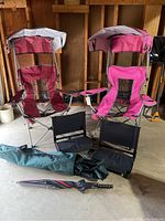 Front view of two pink Renetto Original Canopy Chairs with built-in canopies, two black folding stadium chairs in front, a carrying bag on the ground, and an umbrella.