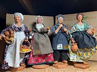 Four full Santon de Provence figurines with boxes behind them on a wooden surface.