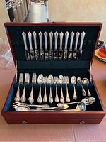 Open wooden chest displaying top row of 12 Towle sterling knives.