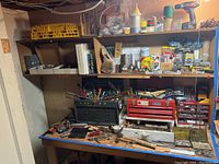 Workbench overview with two metal toolboxes and shelf of supplies