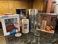 Photo showing all items including boxes for Mikasa decanters, Brookstone flask set, Viski cocktail kit, stainless steel wine chiller, ceramic beer stein, glass decanters, and large wine glass.