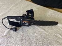 Full view of the Remington electric chainsaw laid flat, showing body, handles, and cutting bar with chain.