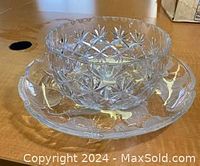 Photo showing stacked glass bowl and serving tray with starburst and crisscross cut patterns on the bowl and floral and leaf design on the tray.