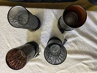 Four cylindrical oil diffuser lamps with black metal casing and tree branch pattern shown from top view, cords attached