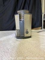 Front view of deluxe electric coffee grinder showing stainless steel body, power cord, and rotary grind selector dial.
