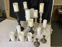 Frontal view of the full collection of electric candles and stands on a light surface with black backdrop