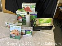 Overall view of FoodSaver vacuum sealer machine and multiple boxes of vacuum bags and rolls arranged on a surface.