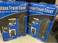 Box of two RJ Sports Deluxe Travel Covers for golf staff bags, showing design features such as in-line skate wheels, shoe compartments, and padded protection. Color black.