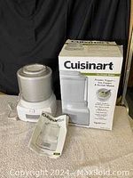 Cuisinart ice cream maker with white and gray base, original box behind, and instruction manual in front