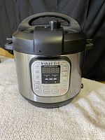 Front view showing the digital control panel with cooking presets and stainless steel body.