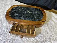Wooden serving tray with a removable dark stone cutting board, drawer partially open to show divided compartments inside.
