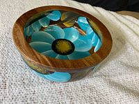 Side angled view of the wooden bowl showing the inside floral painting and wood grain