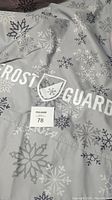 Close-up photo showing Frost Guard logo on gray fabric with snowflake pattern and size tag 78.
