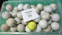 Photo of a plastic bin filled with around 40 used golf balls including one yellow ball.