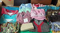Full overview of the clothing and handbags displayed on a table. Shows various tops, pajamas, and bags.
