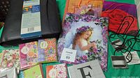 Photo showing business binder, assortment of decorative gift bags, and various note cards arranged on a green cloth.
