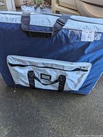 Closed blue and gray carrying bag for the massage table with zipper pocket and handles