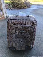 Front view of the rolling carry-on suitcase showing geometric exterior pattern and front zippered pocket.