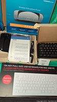 Linksys Wireless-N Broadband Router box with router, manuals, and promotional sheet. Macally 104 key full size keyboard in unopened packaging. Black UHRU wireless keyboard in open box with AA batteries.