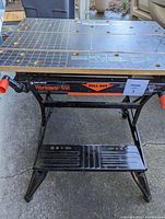 Full view of the Black & Decker Workmate 550 portable folding workbench with black metal frame and work surface showing measurement grid and holes.