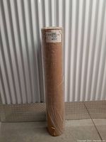 Full view of the kraft paper roll standing upright wrapped in clear plastic, showing the entire roll height and thickness.