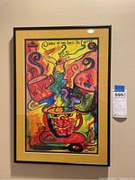 Framed wall art with bright yellow matte and black frame depicting abstract coffee cups and a figure, signed by artist Laurens at bottom right, dated 2002.