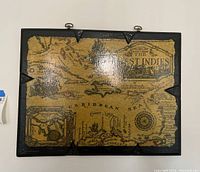 Frontal view of the mounted West Indies map showing black frame, hanging hooks, and aged yellow map surface.