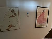 Photograph showing two framed pieces of wall art depicting women; left piece is signed and numbered, right piece is a lithograph print by R.C. Gorman.