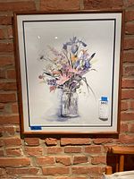Full image of framed floral watercolor wall art against brick wall.