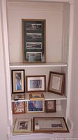 Shelf display with eleven pieces of small framed wall art including various themes and size ranges.