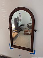 Front view of arched wooden wall mirror showing entire frame and reflective glass.