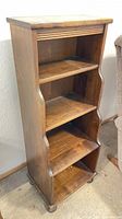 Full view of the small vintage wooden bookcase showing shape, step-down edges, and four shelves