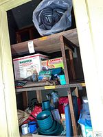 Upper shelves showing Reliance Hassock portable chemical toilet in box, new camping sleeping bag rolled, and some folded fabric items possibly poncho or blankets.