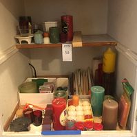 Full shelf showing assortment of various candles and candle holders of different colors and sizes