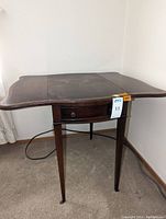 Full view of wood drop leaf table with one leaf extended, showing overall shape and size.