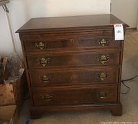 Front view of the dresser showing four drawers with brass handles and pull-out shelf closed