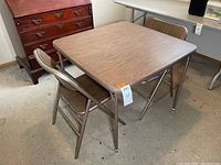 Table and two chairs set arranged in room showing condition and structure