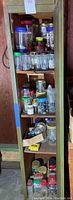 Full view of the green wooden cabinet filled with multiple plastic jars and containers of assorted hardwareincluding screws, nails, bolts, and small parts.