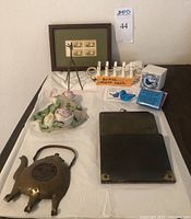 Overview of all items included in the lot showing metal giraffe sculpture, porcelain toast rack, brass teapot trivet, vintage letter holder, bluebird figurine, framed stamps, and a porcelain decorative item