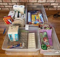 Full lot overview showing all kitchen and gift items grouped in bins on the floor against a brick wall.