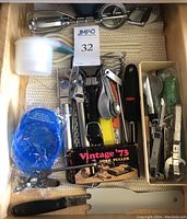 Top view of assorted kitchen utensils including flexible straws, egg beater, measuring cups, and metal utensils.