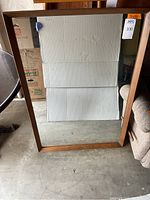Full view of the large rectangular mirror measuring 32x46 inches with wooden frame leaning against a wall.