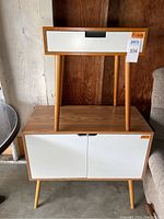 Console table with two white doors, wood finish, standing on angled legs; side table with a single white drawer placed on top of console.